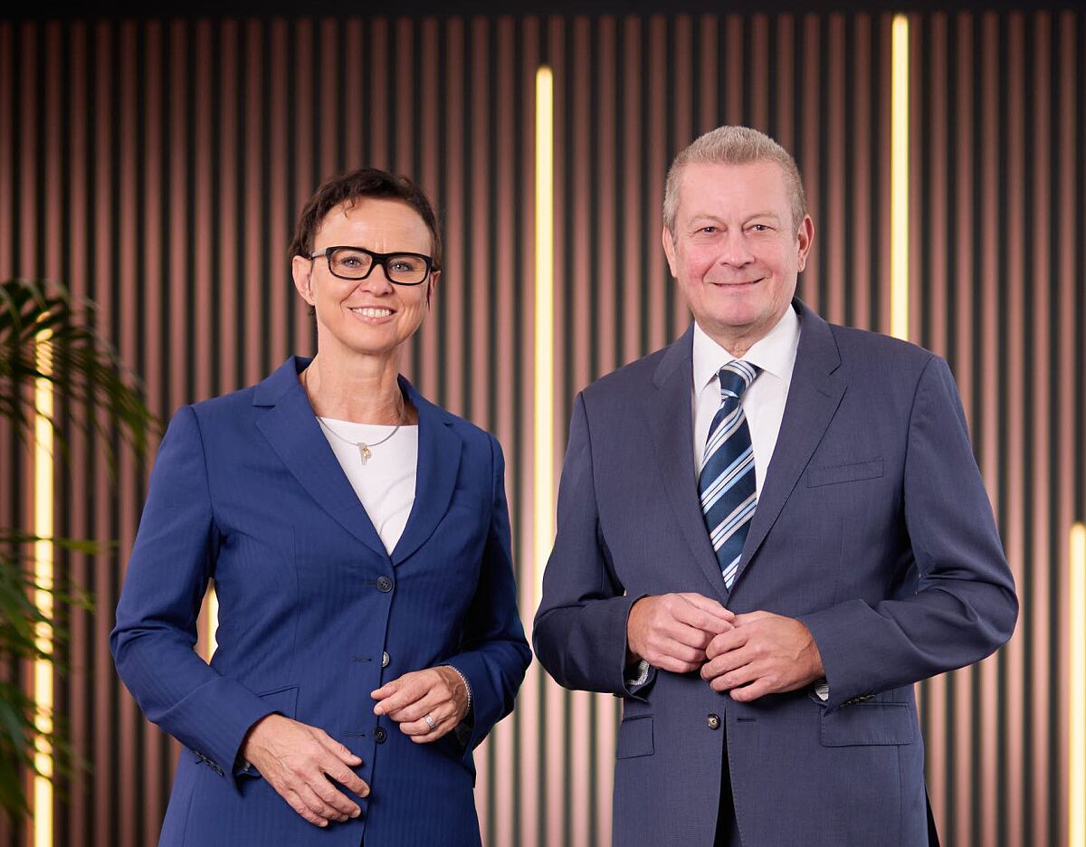 Mag.a Elisabeth Stadler und Dr. Karl Seidl im Porträt vor einer modernen Wandgestaltung.