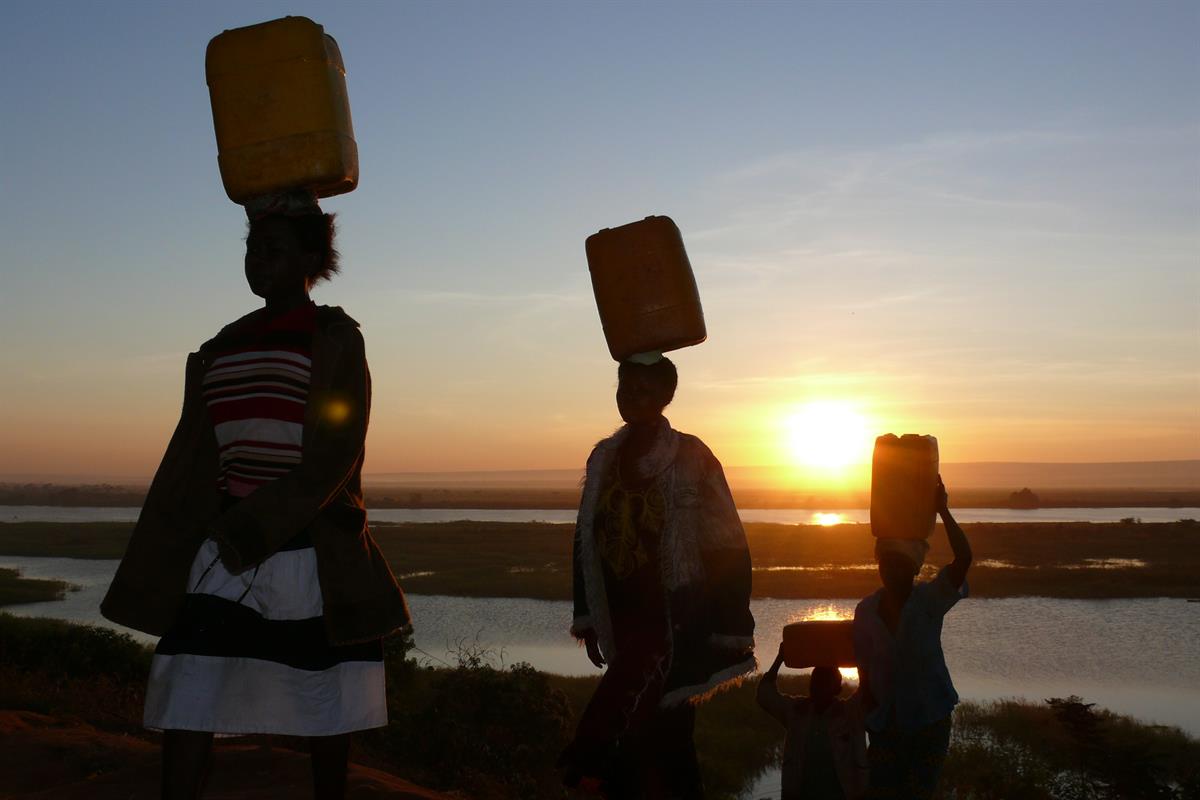 Charity-Aktion Wassertropfen: Frauen tragen Wasserkanister von den sauberen Wasserstellen in der Demokratischen Republik Kongo nach Hause.